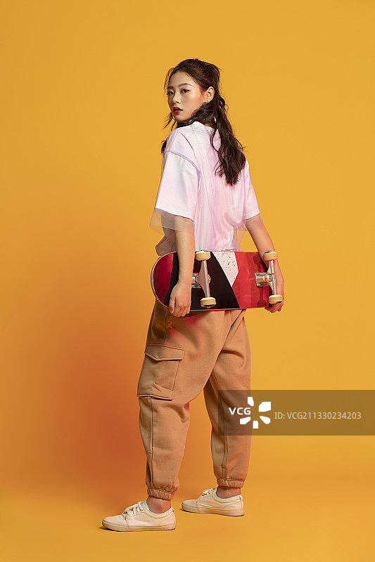 时尚的年轻女孩拿着滑板图片素材