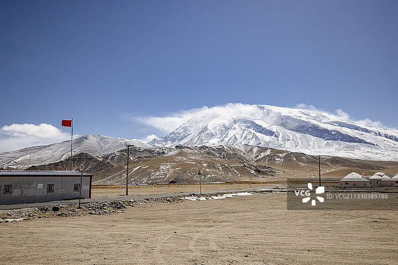 新疆高原上的雪山、枯黄的草地及简易板房图片素材