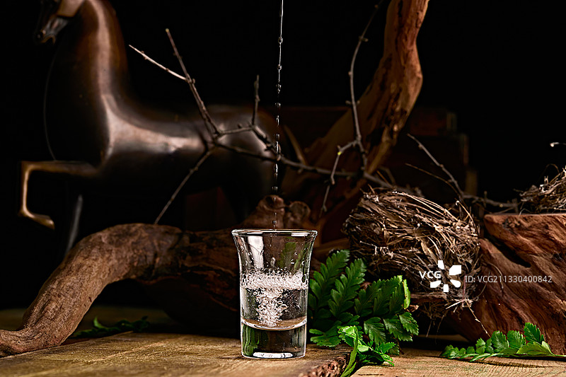 木板上摆放的酒具倒入清澈的白酒激起酒花图片素材