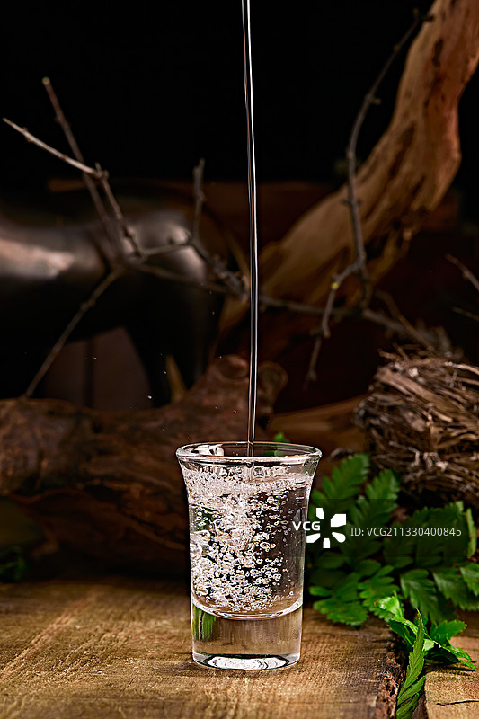 木板上摆放的酒具倒入清澈的白酒激起酒花图片素材