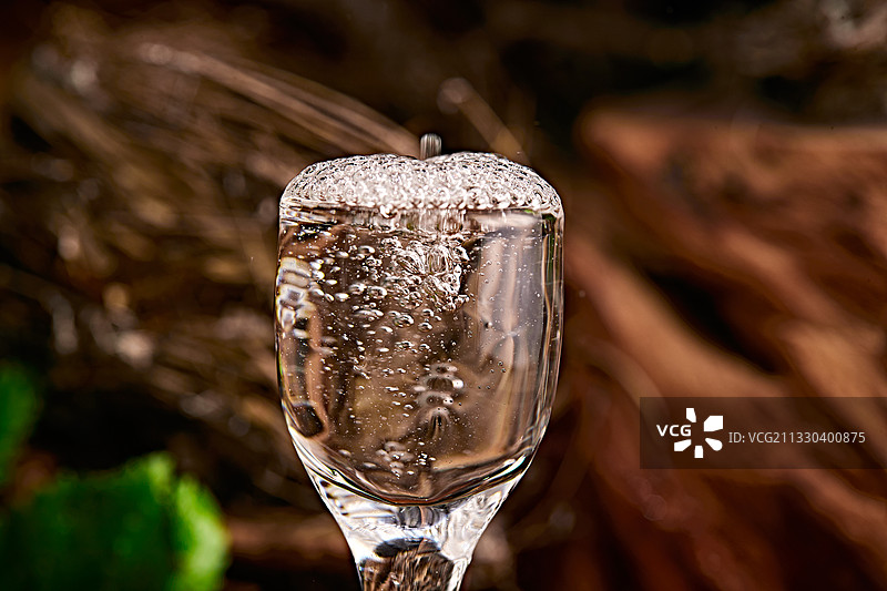 木板上摆放的酒具倒入清澈的白酒激起酒花图片素材
