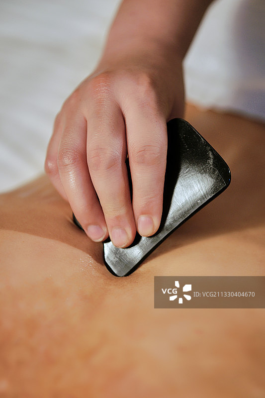 专业的保健技师为顾客做牛角刮痧图片素材