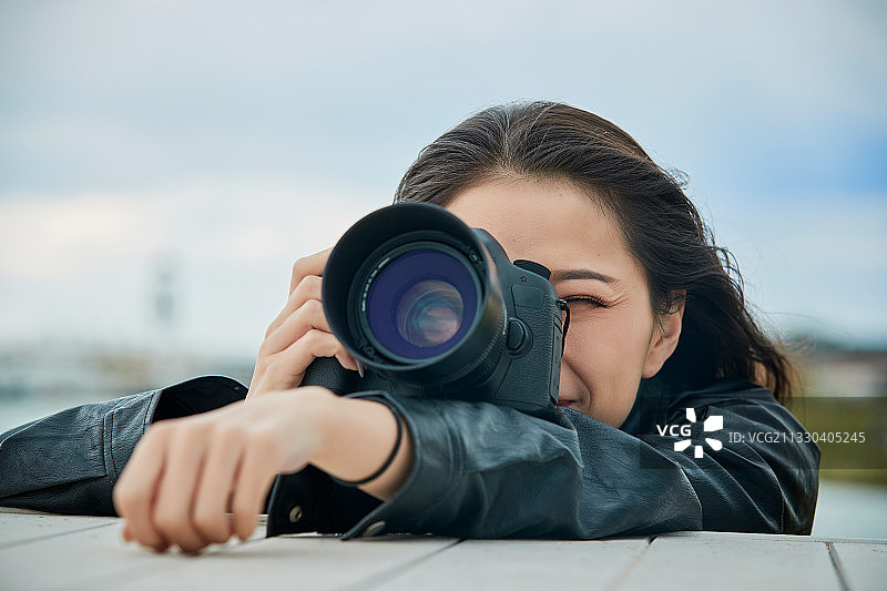 户外湖畔进行拍摄的亚洲青年女性摄影师图片素材
