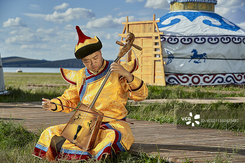 蒙古包前身穿蒙古族服饰拉马头琴的男子图片素材