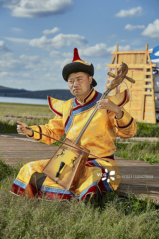 蒙古包前身穿蒙古族服饰拉马头琴的男子图片素材