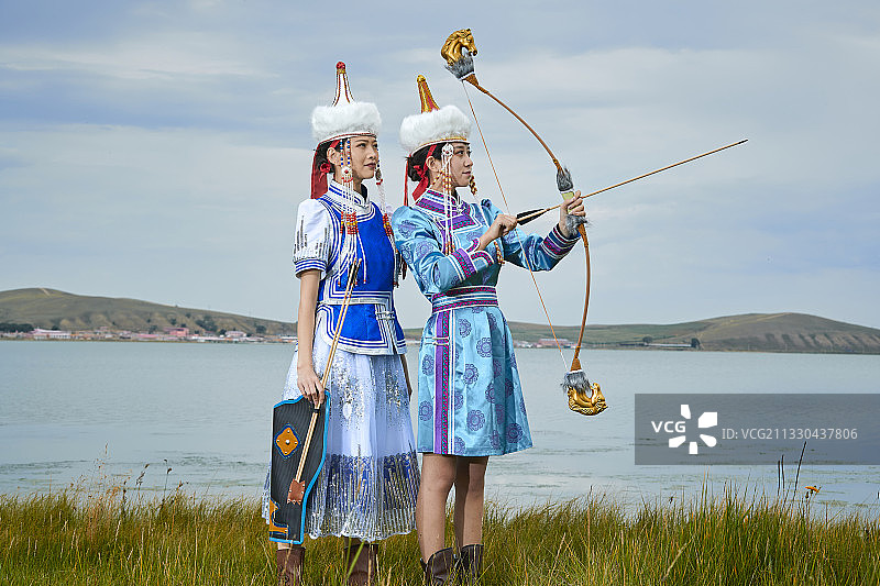 草原上身穿蒙族服饰身挎长弓的少女姐妹图片素材