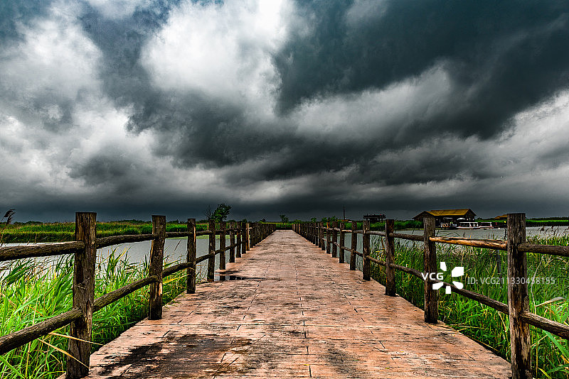 乌云下，一座笔直通往前方的木桥图片素材