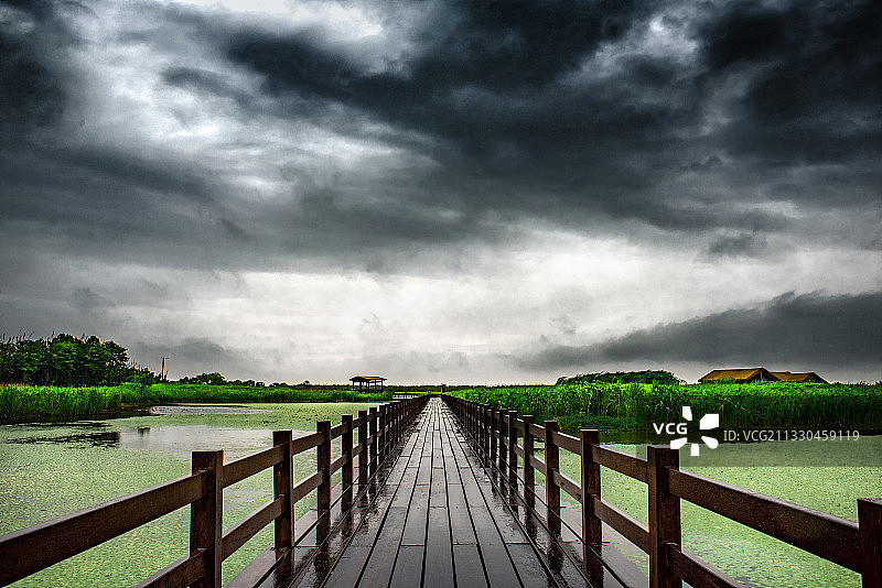 乌云下，一座笔直通向前方的木桥图片素材