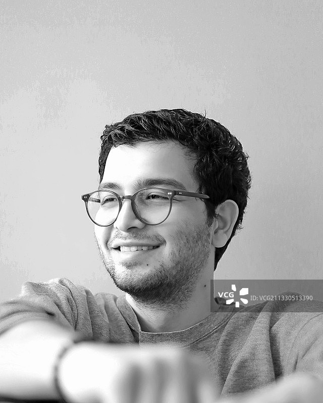 戴眼镜靠墙的微笑年轻人图片素材