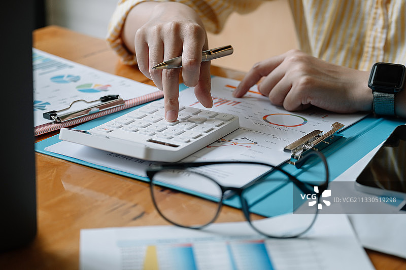 商务女士在办公室的办公桌上使用计算器图片素材
