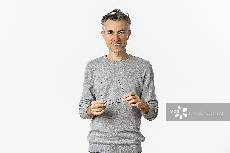 微笑男人在白色背景下手持眼镜的肖像图片素材
