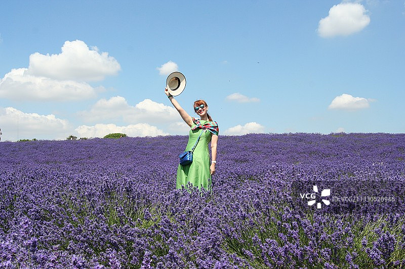 女人戴着帽子站在田野里，背景是天空图片素材