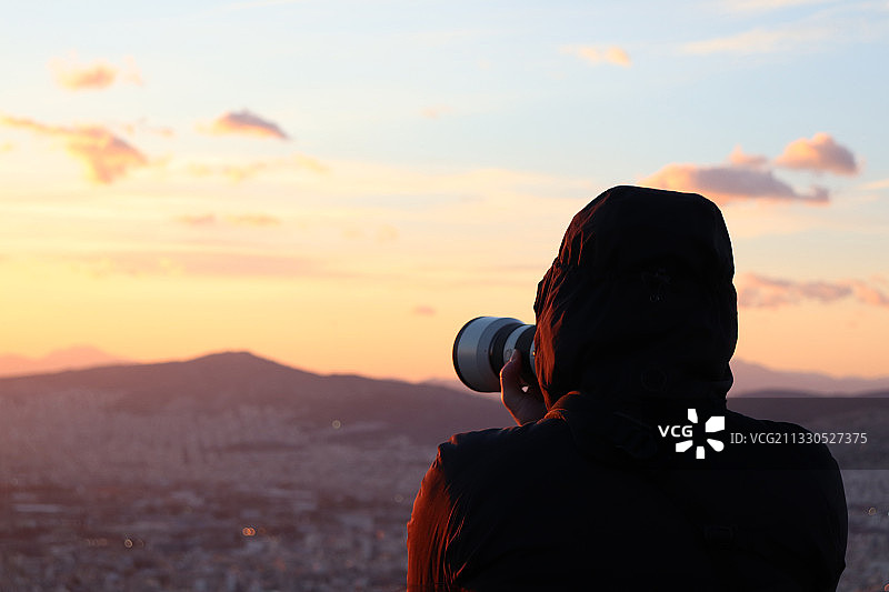 日落时分，男子拍摄天空的背影图片素材