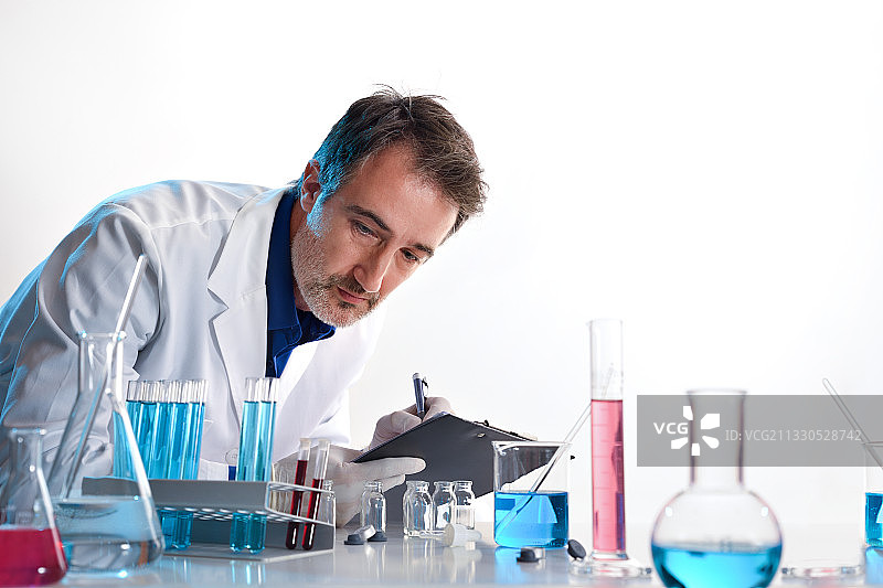 在实验室的桌子上写笔记本的科学家图片素材