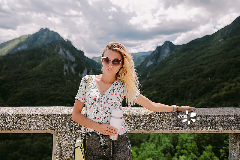靠在山边栏杆上的年轻女人图片素材