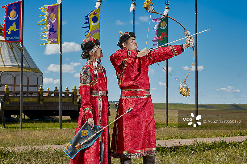 草原上蒙古包前穿蒙古族传统服饰的年轻夫妻图片素材