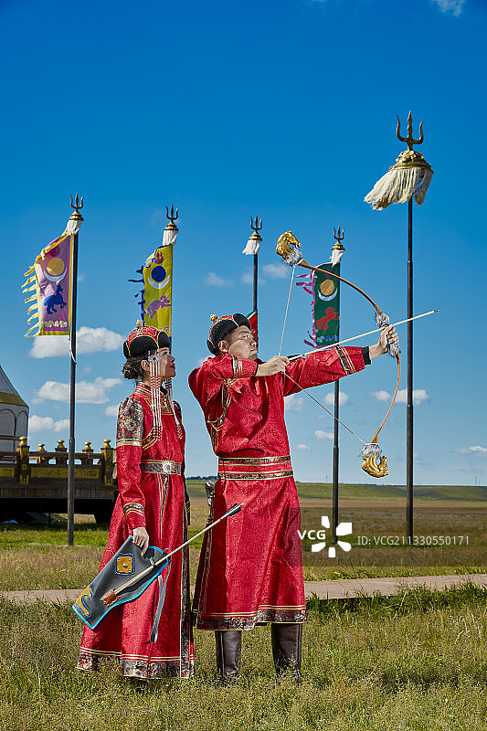 草原上蒙古包前穿蒙古族传统服饰的年轻夫妻图片素材