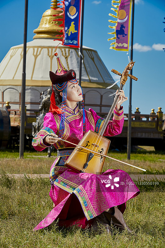 草原上穿着蒙古族传统服饰演奏马头琴的少女图片素材