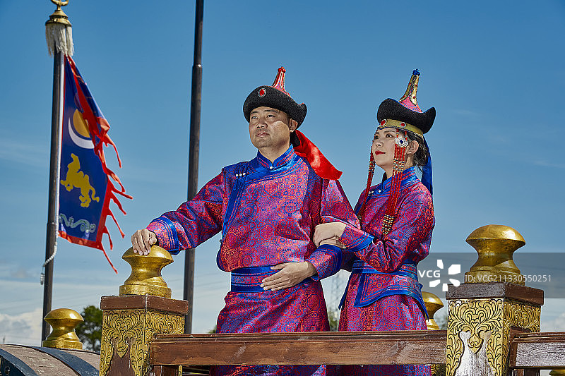 草原蒙古战车上身穿蒙古族传统服饰的年轻夫妻图片素材