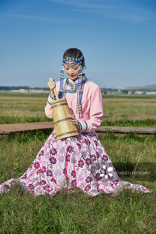 草原上蒙古包前手拿酥油桶的蒙族少女图片素材