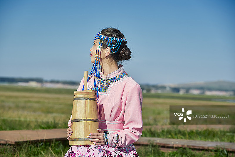草原上蒙古包前手拿酥油桶的蒙族少女图片素材