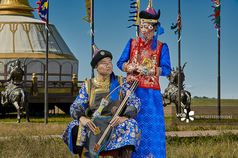 草原上蒙古包前穿蒙古族传统服饰的年轻夫妻图片素材