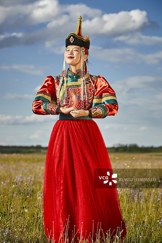 湖畔草原上穿着蒙古族传统服饰的少女图片素材