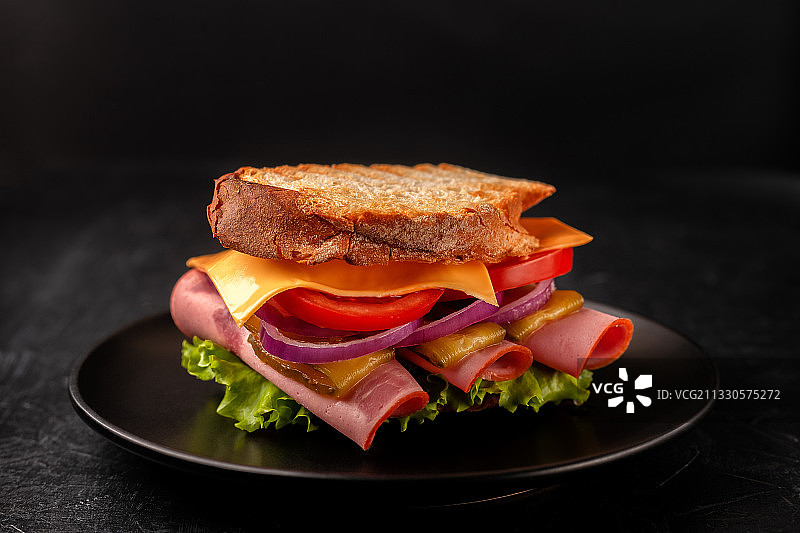 黑色背景桌上的盘中三明治特写图片素材