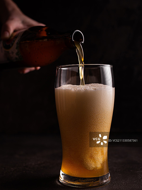 黑色背景下，饮品倒入玻璃杯的特写图片素材