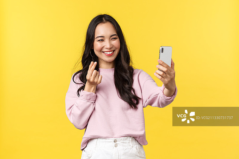 年轻女子在黄色背景下使用手机微笑图片素材