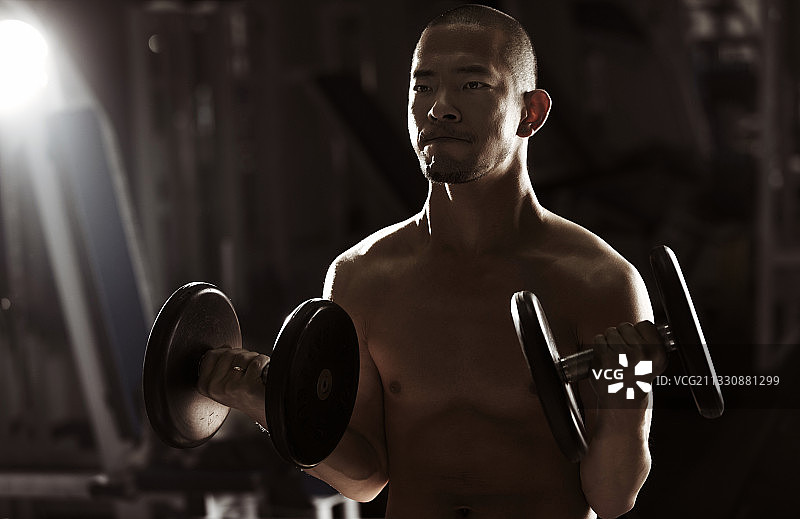 亚洲男人在健身房用杠铃训练图片素材