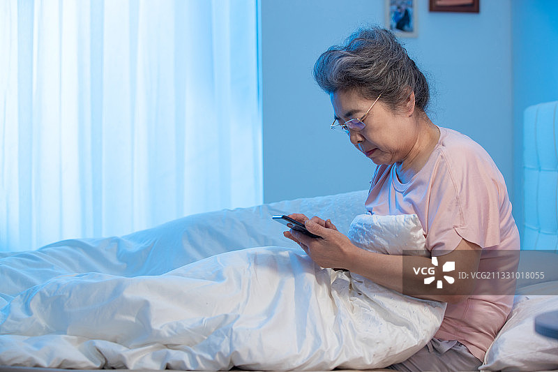 老年人坐在床上看手机图片素材