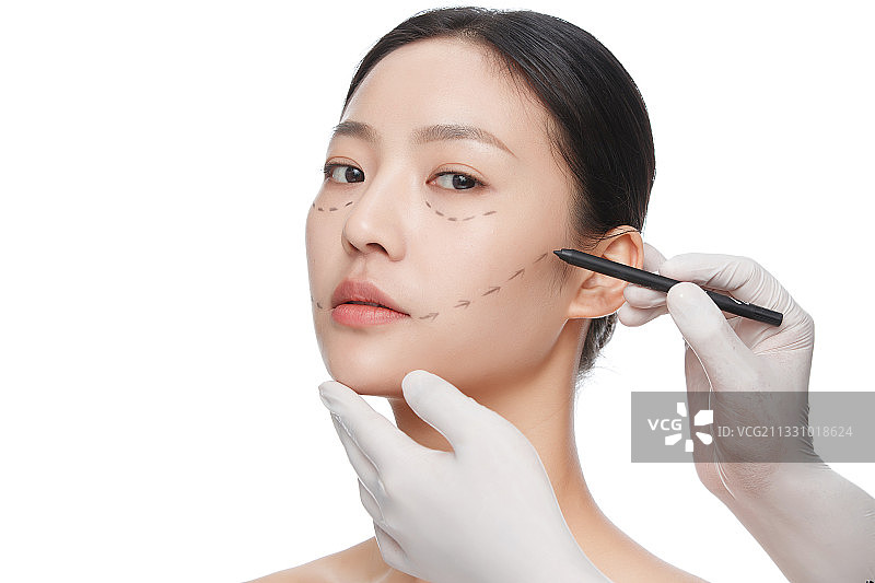 整形医生在青年女人脸上画线图片素材
