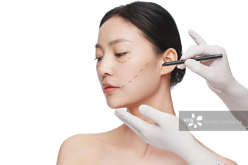 整形医生在青年女人脸上画线图片素材