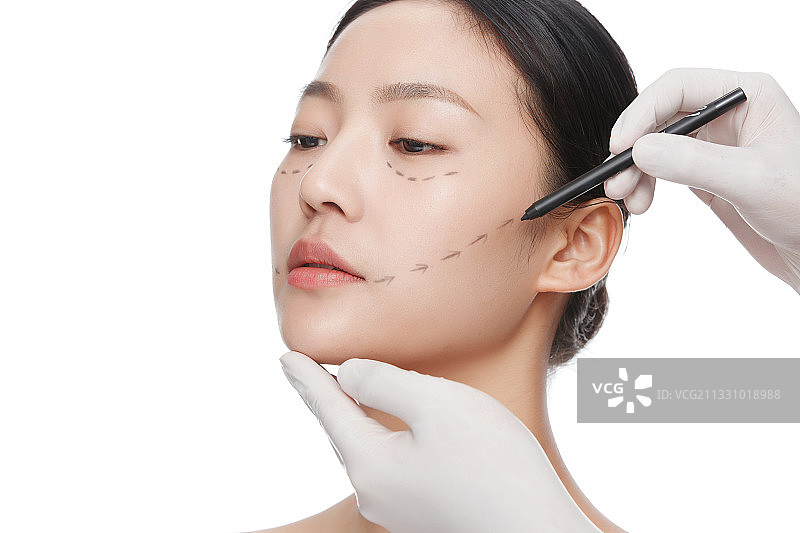 整形医生在青年女人脸上画线图片素材