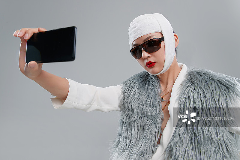 头戴绷带的漂亮女人用手机视频图片素材