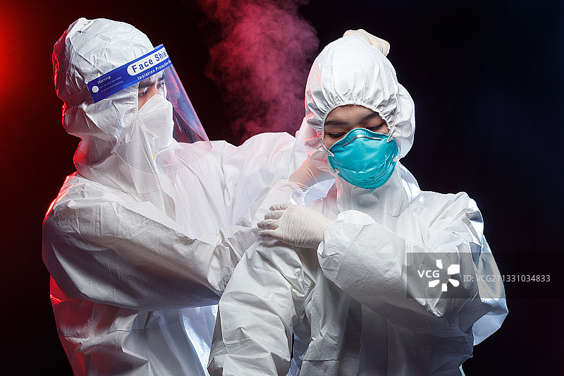 穿防护服的青年男人帮同事调节口罩图片素材