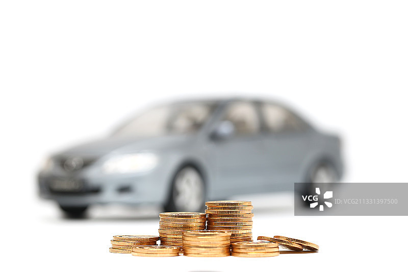 金色硬币放在汽车模型白色背景前图片素材