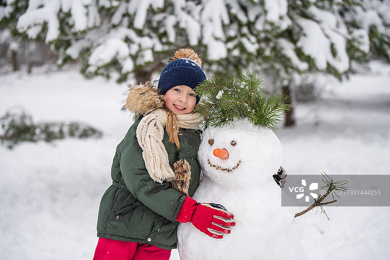 快乐的女孩在雪地里堆雪人图片素材