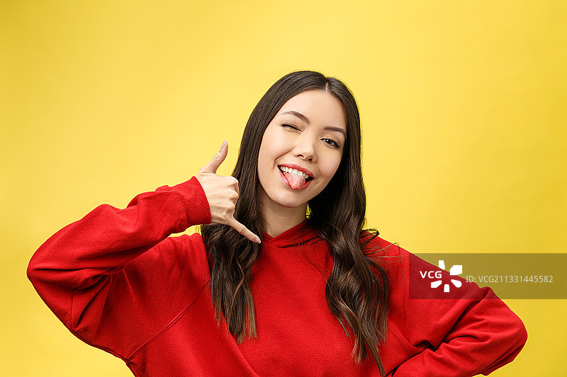 笑容满面的年轻女人在黄色背景下手势的肖像照图片素材