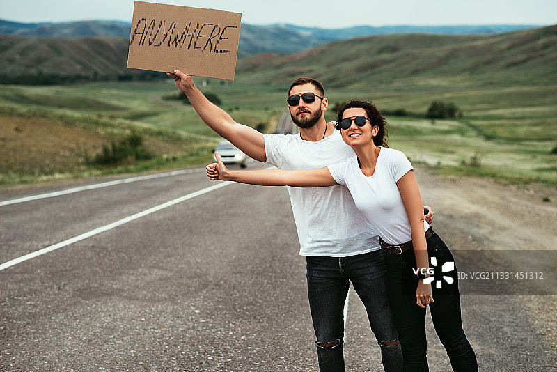 年轻夫妇在路上搭便车旅行图片素材
