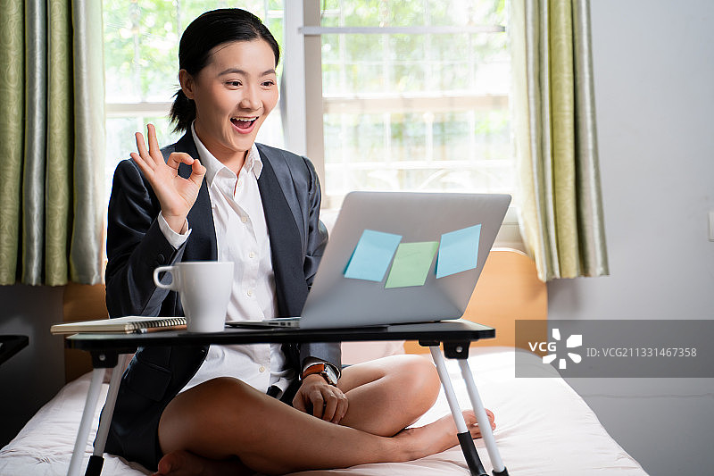 微笑的女商人在办公室的办公桌旁使用笔记本电脑图片素材