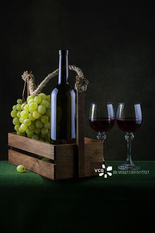 黑色背景下，桌上葡萄与葡萄酒瓶特写图片素材