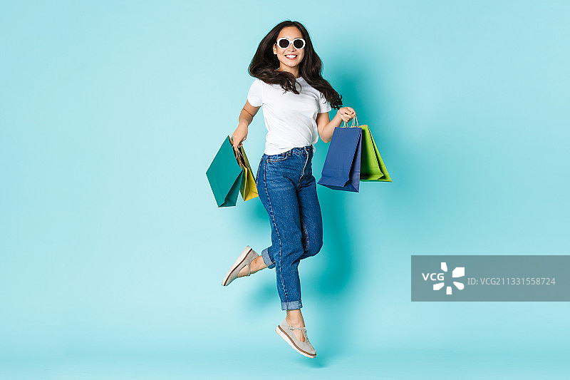 在蓝色背景下手持购物袋的女人肖像图片素材