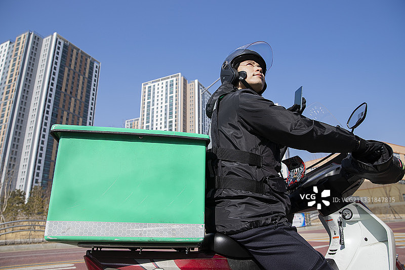 亚洲美食外卖，骑摩托车或电动车的男性快递员图片素材