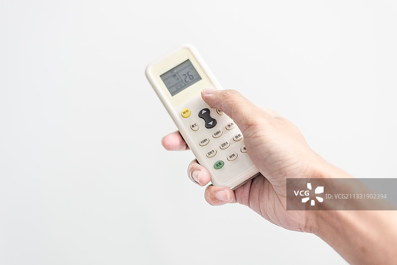 拿着空调遥控器开空调，温度在26度图片素材