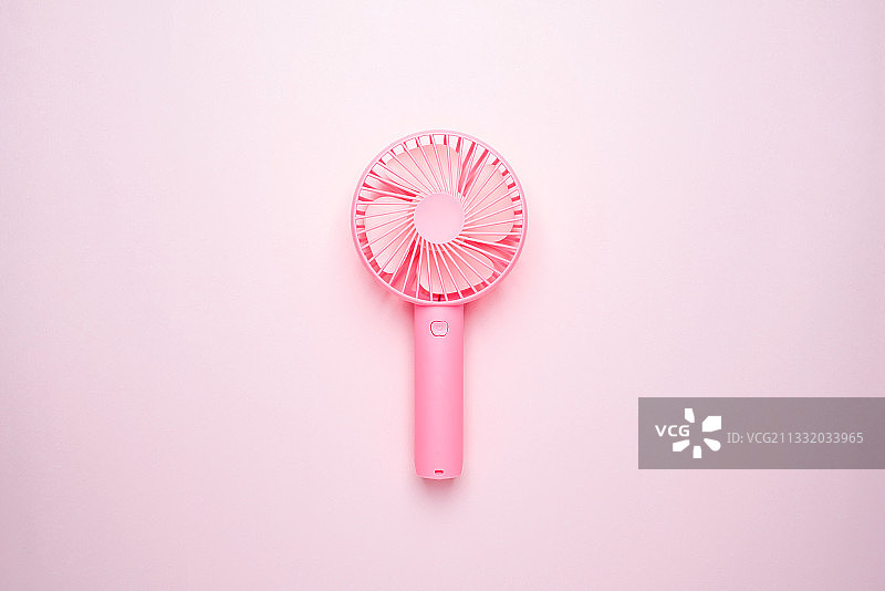 粉红背景上的手持小风扇图片素材