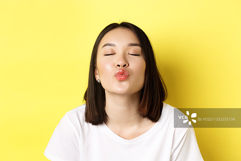 在黄色背景下飞吻的年轻女子图片素材