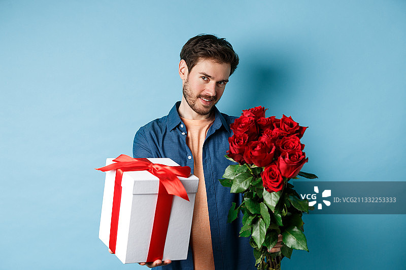 男子手持礼品盒，背景为蓝色图片素材