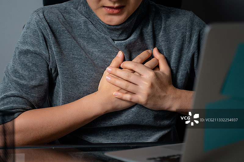 坐在办公室里胸痛生病的亚洲女人图片素材